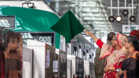 Getty Images Bangladeshi Prime Minister Sheikh Hasina holds a green flag at the opening of the metro rail