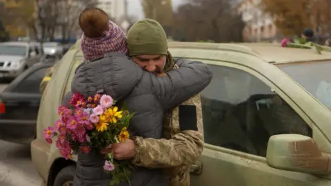 Reuters A Ukrainian soldier is hugged in Kherson