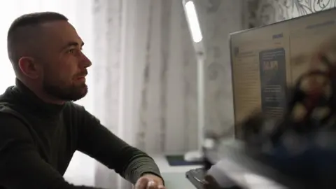 AFP Oleksandr, seated at his computer