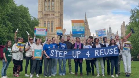 A group holding a banner saying step up to reuse in Westminster