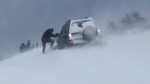 Reuters A man tries to dig his car out of snow