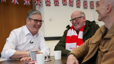 Getty Images Prime Minister Sir Keir Starmer smiles during a meeting with locals at a community centre in Hertfordshire.