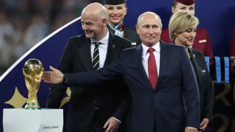 Getty Images Putin gesturing at the World Cup trophy