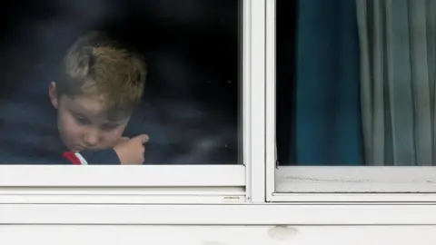 Reuters Blonde boy behind white-framed window