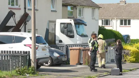 A lorry is wedged into a building with police officers standing nearby
