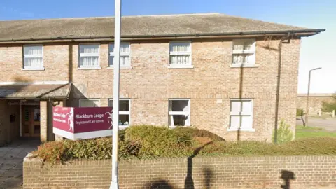 Google Blackburn Lodge - a two story building with a brick wall outside