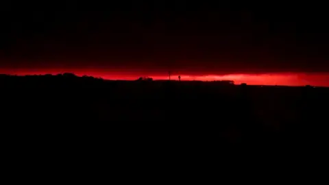 AMY SAVAGE Red glow from fire seen creeping over Mallacoota