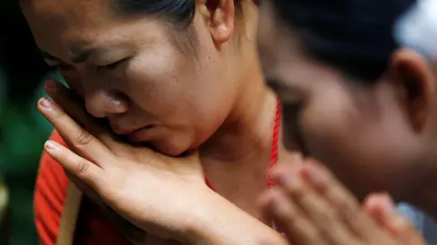 Reuters A relative is pictured looking down in a sad manner, in a close-up image