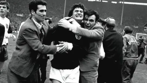 PA Media Jim Baxter being hugged on the Wembley pitch after Scotland defeated England in 1967