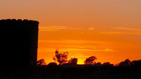 Ruth Ashworth Bright orange sunset with outline of the castle in the foreground