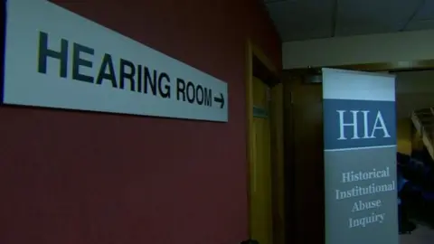 A sign which says 'Hearing Room' pointing towards a door