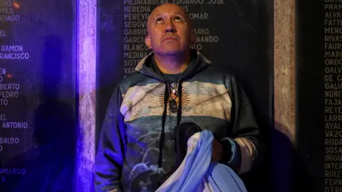 Reuters An Argentinian holds his country"s flag in front of a memorial dedicated to those who died in the 1982 war