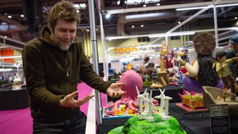 PA Media Comedian Rhod Gilbert delivering his creation during Cake International 2019 at the NEC, Birmingham