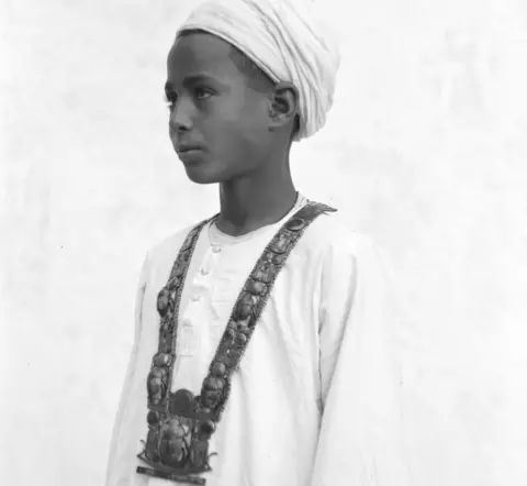 Harry Burton/Griffith Institute, Oxford University An Egyptian boy models a jewelled necklace found in Tutankhamun's tomb