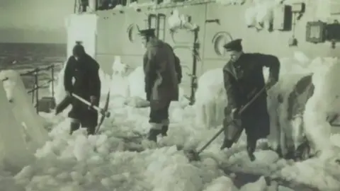 men shovelling ice from ship deck