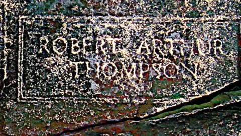 David Stuckey Part of a bronze plaque showing signs of wear and the name Robert Arthur Thompson