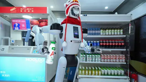 Getty Images A Galbot humanoid robot works at a robot-operated coffee kiosk on March 10, 2026 in Nanning, Guangxi Zhuang Autonomous Region of China. The robot can make coffee, fetch items autonomously, accurately identify various products and interact in multiple languages. 