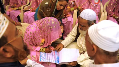 Getty Images woman signing the marriage registry at a mass Muslim wedding in Gujarat in 2015