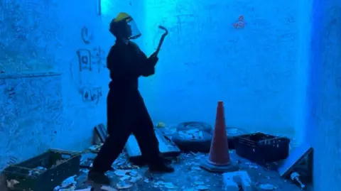 Picture of someone in a rage room surrounded by items to smash