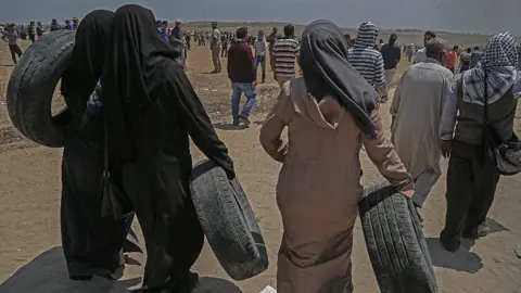 EPA Palestinian female protesters carry tires during clashes after protests near the border with Israel in the east of Jabaliya in the northern Gaza Strip