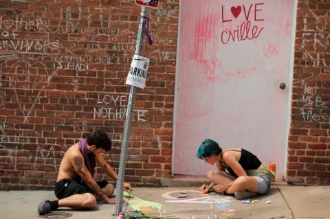 Reuters People draw on a sidewalk near a memorial to Heather Heyer ahead of the one year anniversary of the 2017 Charlottesville "Unite the Right" protests in Charlottesville, Virginia