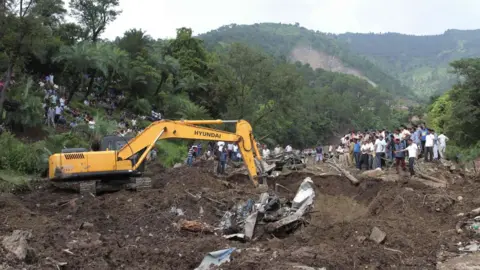 AFP Heavy machinery removes debris as rescue personnel search for survivors and bodies of victims after a landslide along a highway at Kotrupi