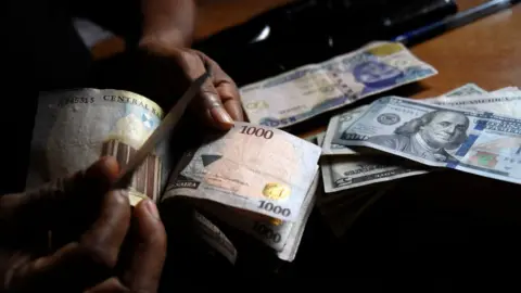 Getty Images Man exchanges naira notes for dollars