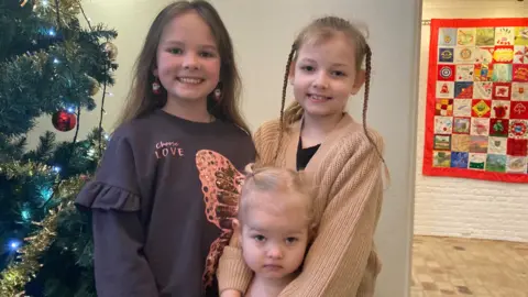 Nadia Gyane/BBC Nika ,10, Soffia, 8, and Zlata, 3, at Ukrainian Christmas event