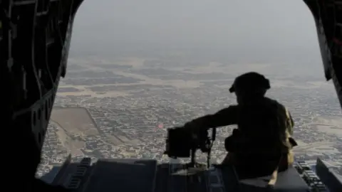 Getty Images US soldier sits in the rear of Chinook helicopter while flying over Kabul on 10 August 2017