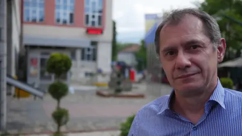 BBC Davor Supa is pictured in a portrait, with the out-of-focus city streets stretching out behind him