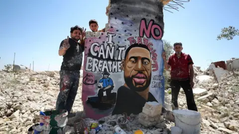 Getty Images painter Aziz Asmar and his two friends standing by a mural of George Floyd