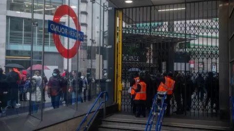 Getty Images Commuters wait in long queues for buses at Victoria Train station as the underground is shut down