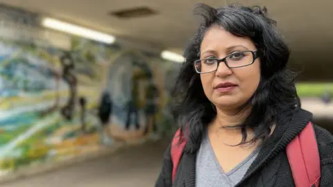 Emma Baugh, BBC Artist in foreground with artwork in the background