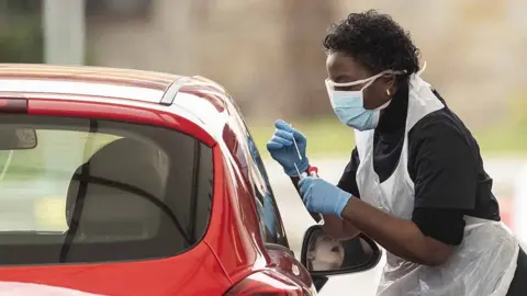 Getty Images A nurse takes a swab at a Covid-19 Drive-Through testing station for NHS staff on March 30, 2020 in Chessington