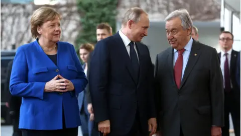Getty Images German Chancellor Angela Merkel, Russian President Vladimir Putin and United Nations Secretary-General Antonio Guterres arrive for an international summit on securing peace in Libya, held in Germany