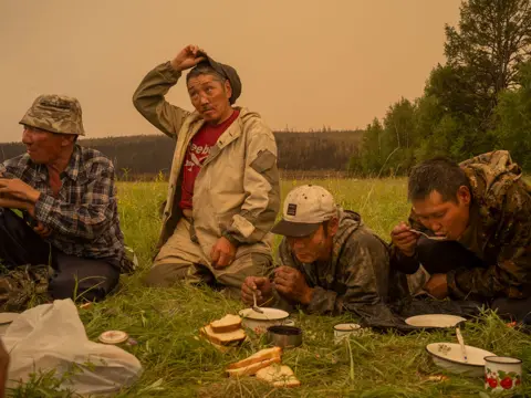 Nanna Heitmann taken for Magnum Photos Local firefighting volunteers take a break for food in a field in Magaras, central Sakha, Siberia, Russia, on 1 July 2021