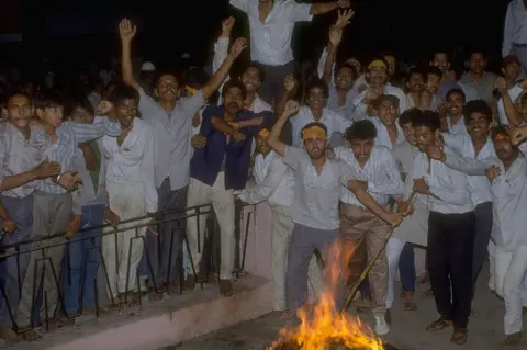 Getty Images Angry youths stoking fire, protesting Mandal Comm. report favouring job quota for lower castes.
