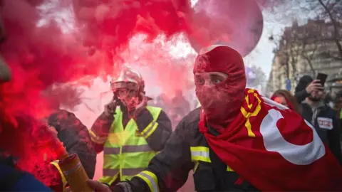 Getty Images A fireman holds a flare aloft during a protest against pension reform plans in Paris, 10 December 2019