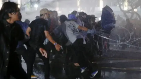 Reuters Protesters run as police use water cannon against them in Bangkok