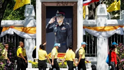 Reuters People walk in front of a portrait of Thailand's King Maha Vajiralongkorn during a rehearsal of his coronation procession which will take place next week in Bangkok, Thailand April 28, 2019.