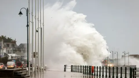 Penzance Council A large wave coming over the barrier in Penzance onto the promenade.