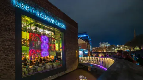 Bristol Light Festival A building is lit up by a light installation in the window. The building has a sign that says Left Handed Giant.