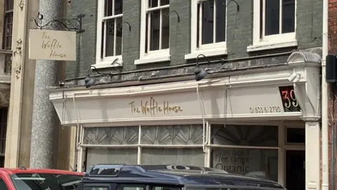 DavidFreezer/BBC The outside of a restaurant called The Waffle House shows a sign hanging outside and its curtains drawn due to it being closed