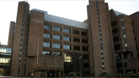 PA Media The exterior of Liverpool Crown Court, with some people seen outside the entrance and the words 'The Queen Elizabeth II Law Courts' on the outside of the building.