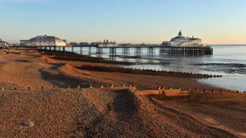 BBC View of the beach at Eastbourne with the pier in the background, all lit by the setting sun