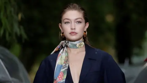 Reuters Gigi Hadid models in Paris wearing a large blue wool coat and a floral silk scarf