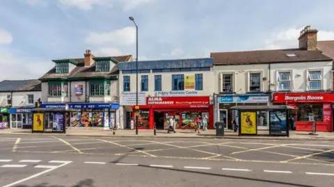 A view of a row of shops next to a road.