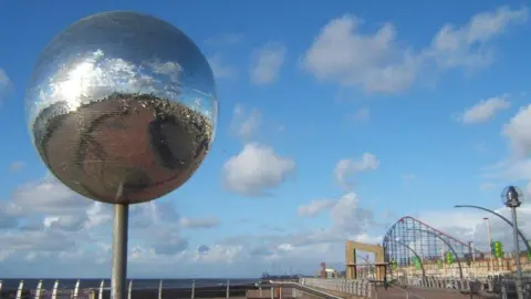 The large glitterball on the south promenade Blackpool with the Pleasure Beach in the background.