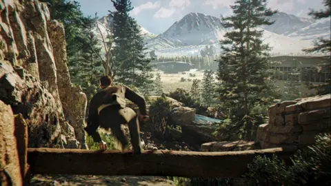 IO Interactive An action screenshot from the new Bond game of the spy jumping over a log in the wilderness.
