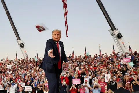Jonathan Ernst / Reuters US President Donald Trump throws a face mask into the crowd